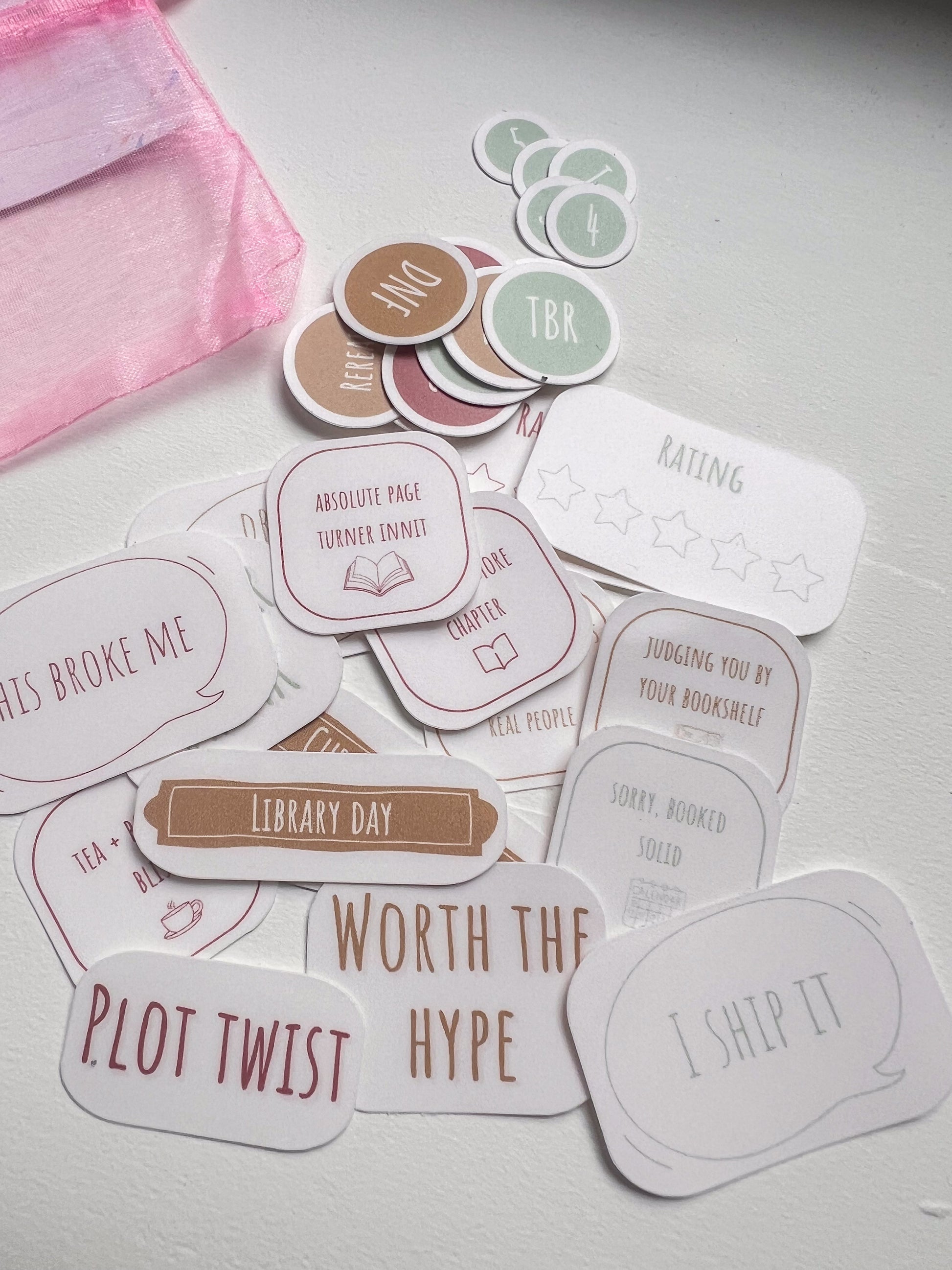 Collection of book-themed stickers on a light surface with a pink pouch.