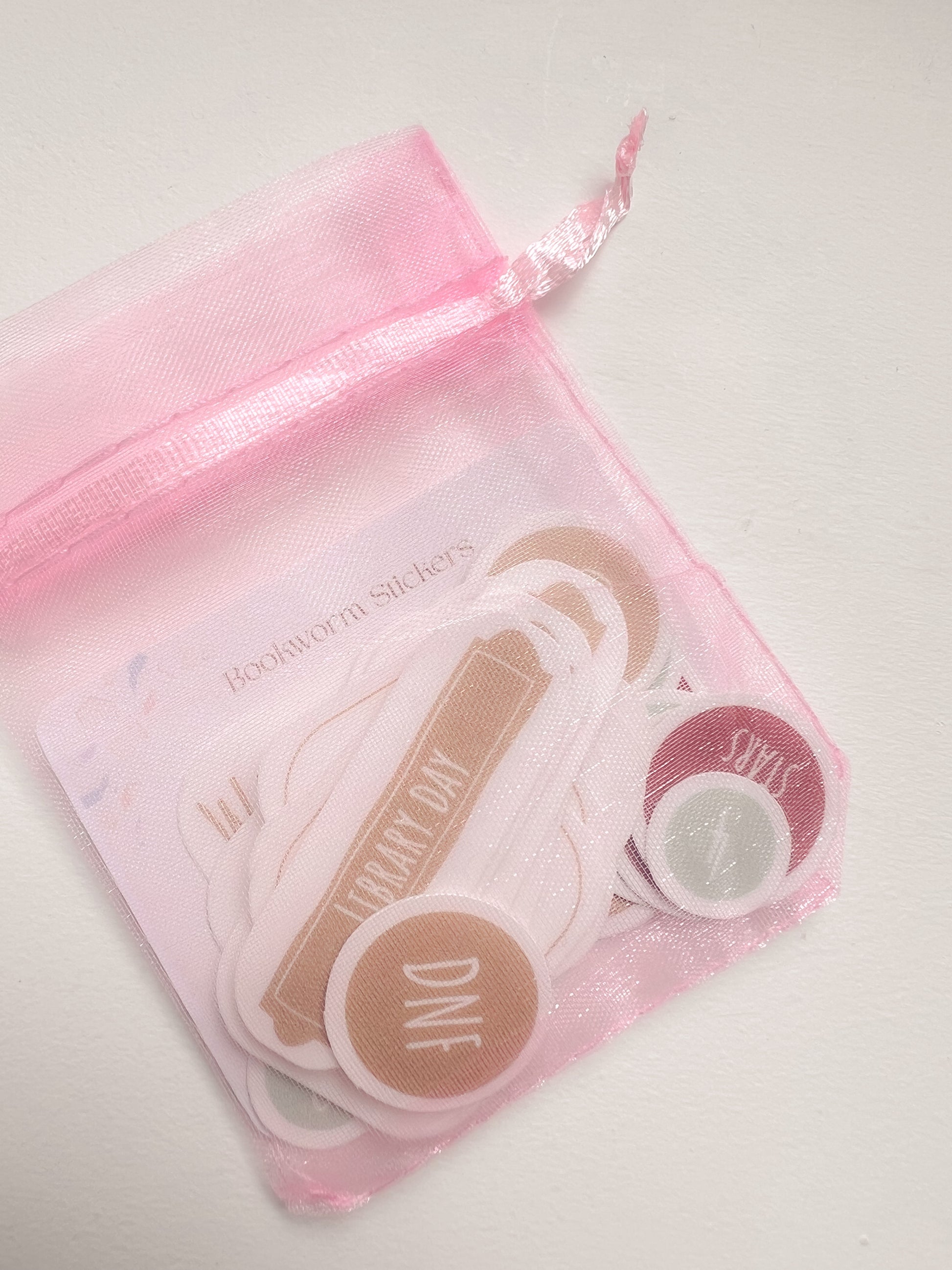 Set of stickers in a pink drawstring bag on a white background